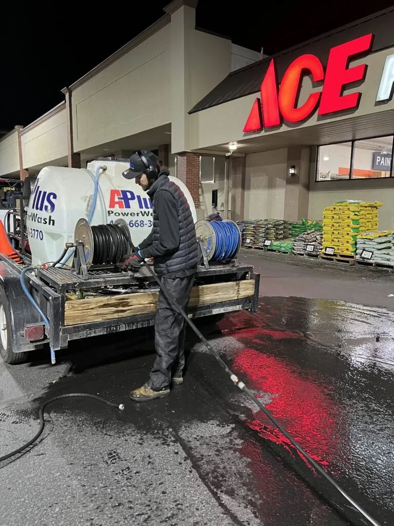 Technician with pressure washing trailer equipment during nighttime commercial work