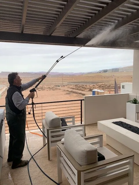 Technician pressure washing an outdoor patio pergola structure